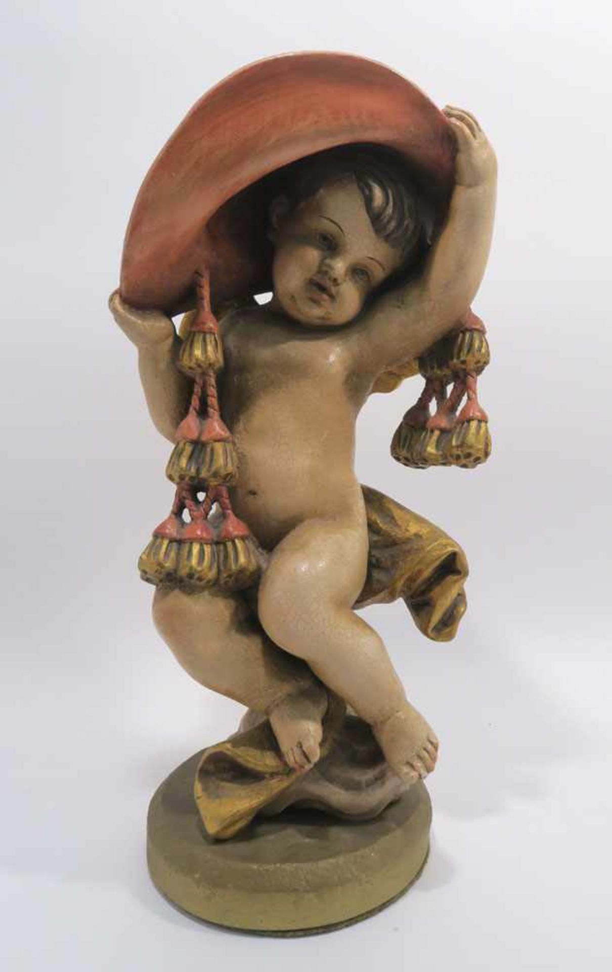 Putto mit großem HutBarockstil. Holz, Farb- und Goldfassung. Min. besch. H. 55 cm.