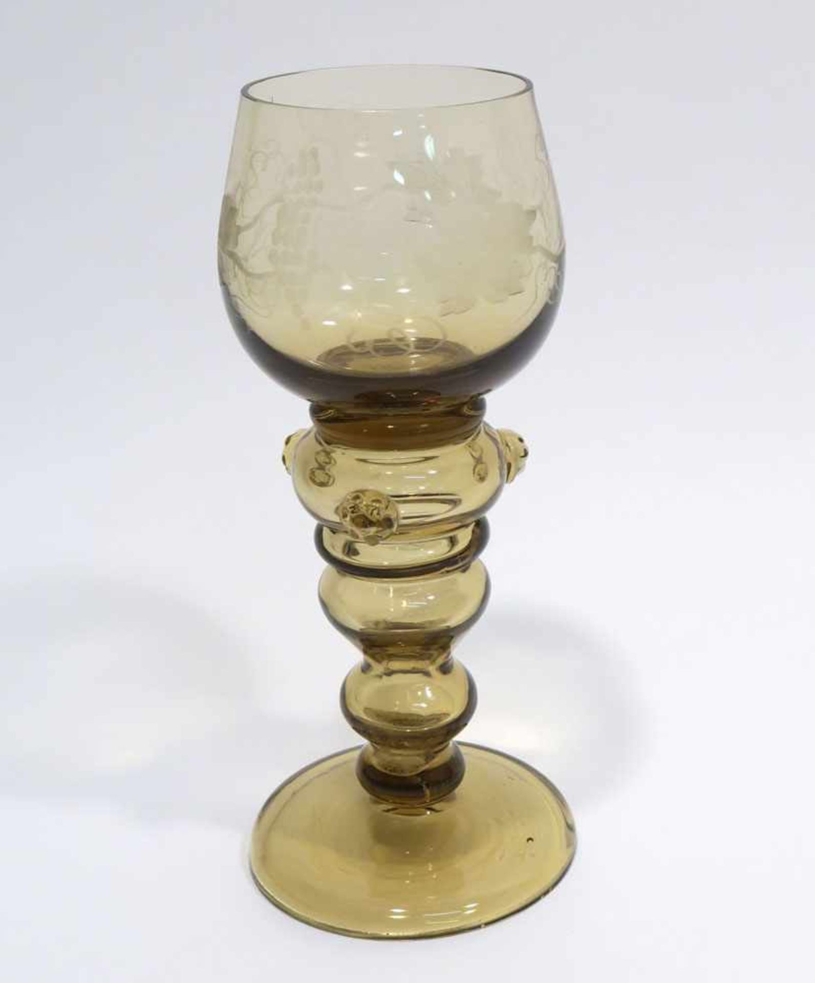 RömerBräunliches Glas. Hohlbalusterschaft, drei aufgesetzte Noppen, geschnittener Weinlaubdekor.