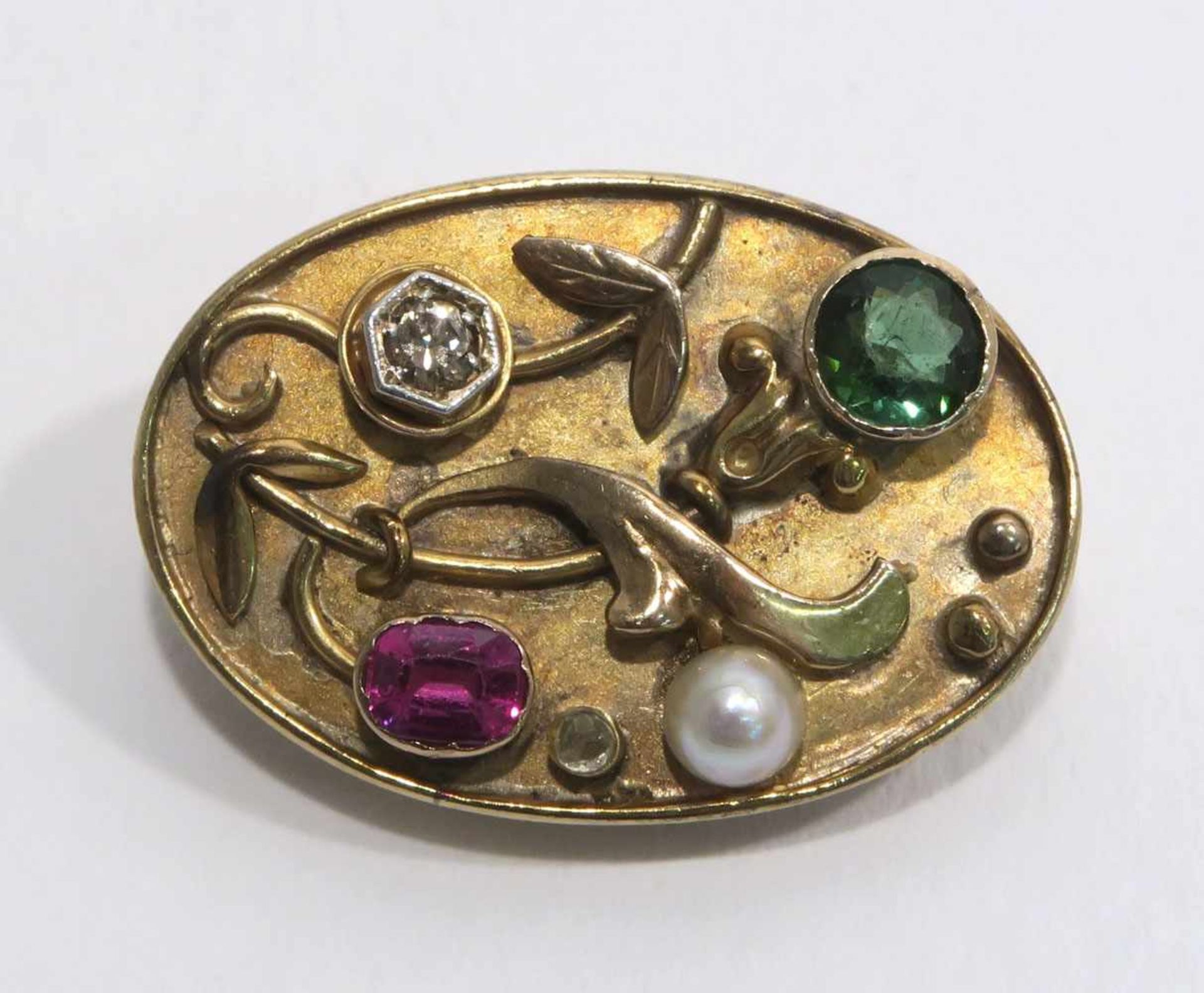 Brosche18 K GG. Ovale Brosche mit einem Brillant, Rubin, einem Turmalin und einer Perle besetzt. 2,7