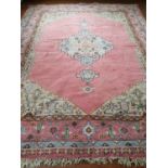 A Pink ground Rug decorated with sky blue medallions. 420 x 320 cm.