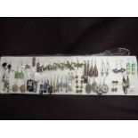 A tray of 25 pairs of drop earrings including dragon flies, elephants, enamelled and glass