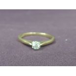 A lady's dress ring having a diamond solitaire in a claw mount to raised shoulders on a 9ct gold