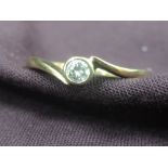 A lady's dress ring having a diamond solitaire in a collared mount to crossover shoulders on a 9ct