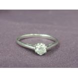 A lady's dress ring having a diamond solitaire in a claw mount to raised shoulders on a 9ct white