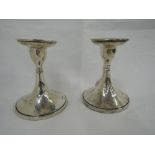 A pair of Edwardian silver candle sticks of short form having waisted columns to flared circular