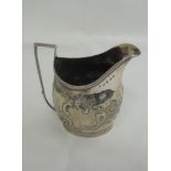 A Georgian silver cream jug of helmet form having floral repousse decoration, plain cartouche,