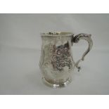 A Georgian silver tankard/mug having foliate and scroll repousse decoration with monogram to