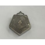 A white metal heptagonal compact having pendant clasp, engine turned decoration to front and