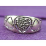 A lady's shaped band ring having central diamond chip heart flanked by pierced hearts on a 9ct white