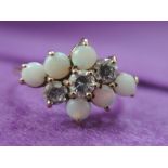 A lady's dress ring having a cubic zirconia and faux opal diamond shaped cluster in a raised claw