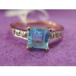 A lady's dress ring having a central princess cut topaz style stone in a claw mount with diamond set