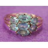 A lady's dress ring having a cluster of blue topaz style oval stones to triple open shoulders on a