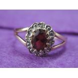 A lady's dress ring having a garnet and diamond cluster to open shoulders on a 9ct gold loop, size