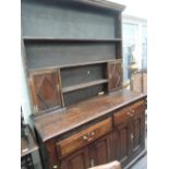 A late 19th century oak dresser in the 18th century style having Delft rack with cupboards over 2