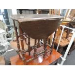 An early 20th century oak occasional table having oval drop leaf top on bobbin gate legs