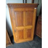 A 19th century golden oak corner wall cupboard having panel door