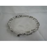 A silver salver of plain form having pie crust rim and trefoil shell feet, Birmingham 1962,