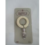 A silver rattle modelled as a soldier with white plastic teething ring, still attached to retail