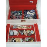 A jewellery box containing a selection of costume jewellery including brooches and necklaces