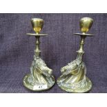 A pair of brass candlesticks modelled as horses heads and horse shoes