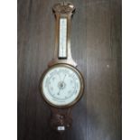 An Edwardian oak frame aneroid banjo barometer having carved decoration with thermometer scale and