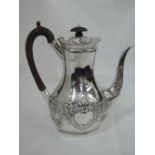 A Victorian silver coffee pot having fruit wood handle and knop, repousse floral decoration and