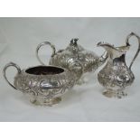 A Victorian three piece silver tea set having scroll and floral repousse decoration, plain