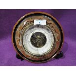 A vintage porthole style barometer with bevel edged glass and visible mechanism