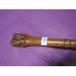 A vintage walking stick or cane in hand carved wood with human fist style handle