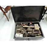 A metal tool box containing a selection of vintage tools including vice, hand drill, mallet etc