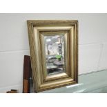 A vintage mirror with gilt style frame and bevel edged glass
