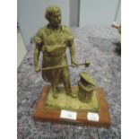 A vintage brass cast model of a blacksmith working in forge