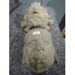 A set of two stone carved type gargoyle heads possible corbel sculpture or religious wall sconce