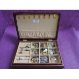 A wooden jewellery box containing a selection of brooches, rings, pins etc