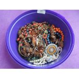 A tub of costume jewellery including rough cut Baltic amber, Judy Laws pendant etc