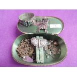 A small travel jewellery case containing a selection of white metal jewellery including bangle