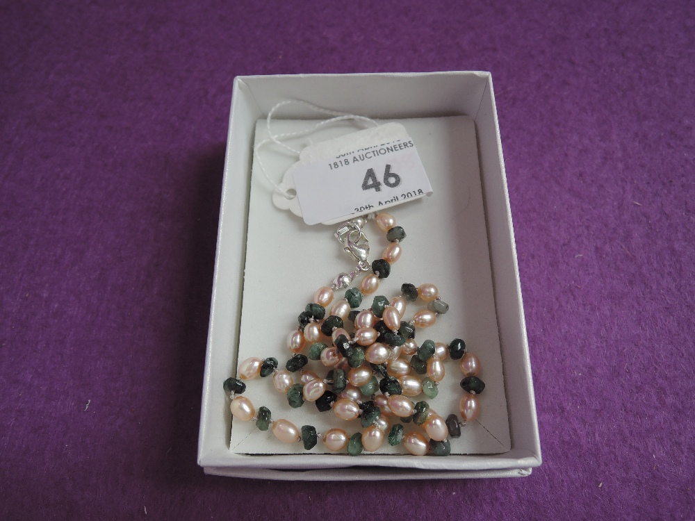 A string of peach coloured fresh water cultured pearls interspersed by rough cut emerald beads