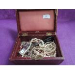 A vintage jewellery box containing a selection of costume jewellery including simulated pearls