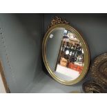 A vintage oval mirror with bevel edged glass and plaster gilt effect frame