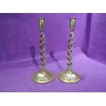 A pair of brass cast candle sticks with twist stem body