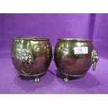 A pair of small brass cast containers with eagle claw and ball feet and lion head handles