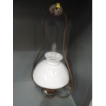 A vintage oil burning lamp with ceiling fitting and milk glass shade