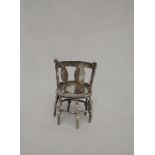 A miniature silver chair modelled as Bulwar Lytton's chair having bow back and six bobbin legs,