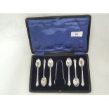 A cased set of six silver coffee spoons with matching sugar nips having moulded decoration to