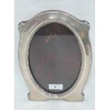 A silver photograph frame of plain shaped oval form with wooden easel back, Chester 1912, J & R