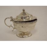 A large silver lidded mustard pot of circular form having facetted decoration to body and