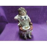 A vintage ceramic figure of large form, child feeding puppy dog,