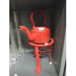 A vintage cast iron kettle and stand in red