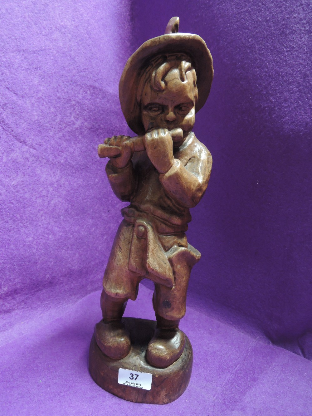 A carved treen boy playing a flute