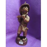 A carved treen boy playing a flute